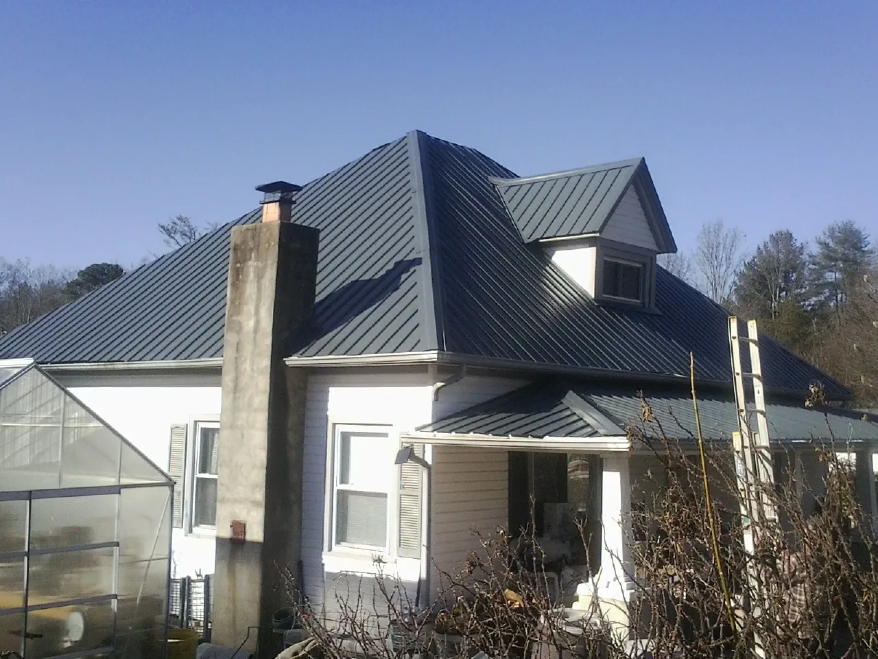 Dark blue standing seam metal roof on a white farmhouse with dormer — Slate & Tile Roof Repair by Roofing Brothers in Lopez Island