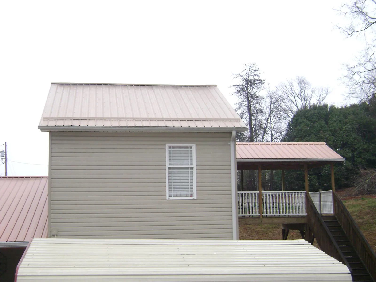 Tan metal roofs on a two story addition and attached porch, from a Roof Replacement job in Lopez Island