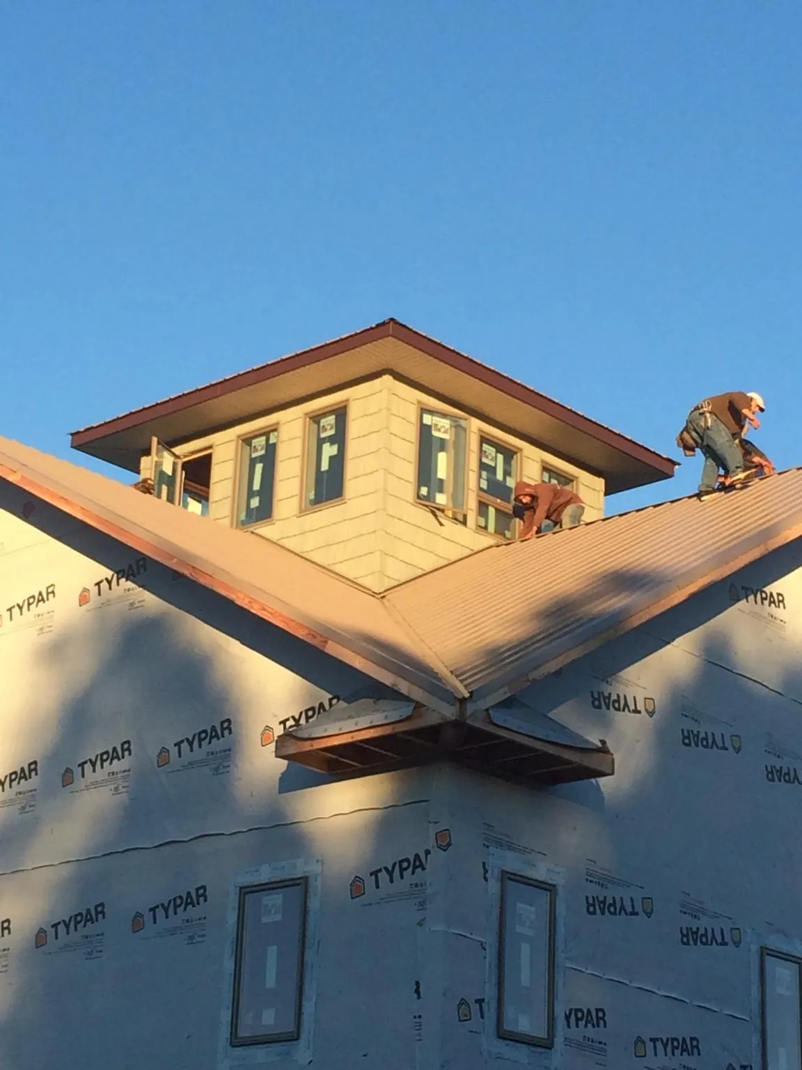 Roofers working around a rooftop cupola on a new metal roof at sunset — Roof Waterproofing in Lopez Island by Roofing Brothers